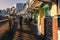 The low afternoon sun shines through the balustrade forming shadows on the pathway and illuminating the cafes and restaurants