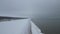 Low altitude aerial shot flying along snow covered beach. Calm sea