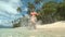 LOW ANGLE: Active young woman runs in her bikini along sandy beach in summer.