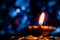 Low angle, closeup of a beautiful earthen lamp glowing in the dark with blue bokeh in the background, on a pile of coins in Diwali