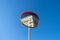 Low-angle closeup of convex traffic mirrors against a clear sunlit sky reflecting a building