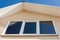 A low angle closeup view of roof upper floors of a house in daytime against blue sky.