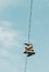 Low-angle of a cluster of shoes hanging from an overhead power line against a blue sky background