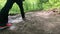 Low angle footage of feet walking on forest trail.