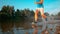 LOW ANGLE: Glassy water droplets fly towards camera as jogger runs in the stream