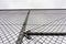 Low angle grayscale shot of a metal wired fence under a clear sky