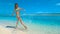 LOW ANGLE: Joyful girl in bikini kicking and splashing the glassy ocean water.