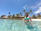 LOW ANGLE: Joyful young woman in bikini looking around the tropical seascape.