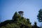 Low-angle of a lighthouse in the forested hill, sunlit, clear sky background