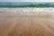 Low angle photo from ground level - beach sand wet from sea, drops of water in air, small waves and blurred ocean in distance. Ab