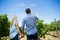 Low angle rear view of couple holding wineglass at vineyard