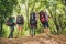 Low angle rear view of four tourists, walking in autumn forest,