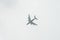 Low angle shot of an airplane soars through the sky, against a backdrop of white fluffy clouds