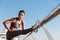 Low angle shot of attractive fit woman workout on a pier, stretching her leg before jogging training. Girl warming-up