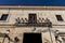 Low angle shot of a building\'s entrance with lights and balcony with flowerpots