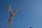 Low angle shot of a crane under a blue sky with several metal cords attached to it