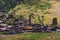 Low-angle shot of Dartlo village view with old, stone houses and people in fields forested mountains