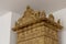 Low angle shot of a decorated golden column captured by a white wall