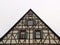 Low angle shot of a half-timbered A-frame house roofing with windows against a white sky