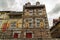 Low angle shot of a high brown building with red doors under the crazy cloudy sky