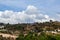 Low angle shot of mountain with small town and clouds covered the blue sky