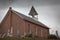 Low angle shot of an old brick church against a cloudy sky