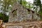 Low angle shot of old stone ruins of a forgotten lodge surrounded by greenery