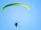 Low angle shot of a person in powered paragliding under a clear blue sky