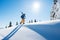 Low angle shot of a skier walking on top of the mountain with his skis on his shoulder on a sunny winter day