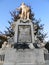 Low angle shot of a statue of Mozart in Austria behind a tree under a blue sky