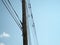 Low angle shot of a tall electric post with a lot of cables attached to it during the midday