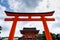 Low angle shot of a Torii gate against a cloudy sky at Fushimi Inari Taisha Kyoto Japan
