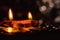 Low-angle shot of two earthen lamps with erect flames and coins in the foreground in Diwali and Dhan-teras concept