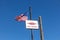 Low-angle shot of the US national flag and a self-parking billboard against a blue sky