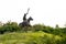 Low angle shot of Warrior Bhai Maali Singh statue sitting on horse against trees and sky in the background. historical monument