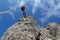 Low angle shot of a woman rappelling down a rock against a blue cloudy sky