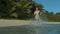 LOW ANGLE: Smiling woman jogs in the shallow part of the ocean along the coast