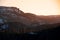 Low-angle of snowy, forested mountains in sunrise with sky covered with sun rays background