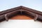 Low angle top view photo of brown roof corner wooden elements on top of small comfortable house with white walls