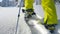 LOW ANGLE: Unrecognizable male splitboarder hikes up a glistening snowy meadow.