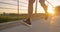 LOW ANGLE: Unrecognizable young man jogs across asphalt bridge at golden sunset.