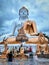 Low angle vertical shot of a huge beautiful Buddhist half-golden statue and smaller statues below