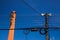 Low angle view against blue sky on isolated high voltage power poles with electric wires, distribution transformer and