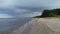 Low angle view of beach and sea with rain clouds. Coastline perspective with rolling waves