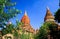 Low angle view beyond trees on  isolated red domes of ancient buddhist brick stone temples against blue sky -  Bagan, Myanmar