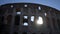 Low-angle view exterior facade of ancient ruined of Roman Colosseum amphitheater during sunset on background of blue sky