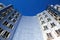 Low angle view on Gehry house with curved silver shiny futuristic metallic aluminium facade with windows against dark blue clear c