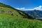 Low angle view of green meadow and alpine village with high mountains under blue sky. Austria, Tirol, Zillertal, Zillertal, High A
