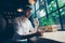 Low angle view of a handsome brunet guy entrepreneur having a coffee break in a loft styled restaurant, looking serious, well dres