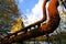 Low angle view on isolated curved corroded pipeline against blue sky and trees